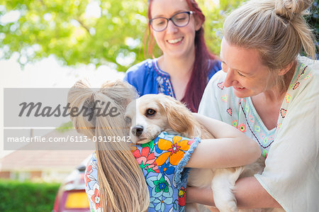 Lesbian couple and daughter hugging cute dog