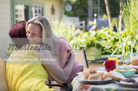 Affectionate lesbian couple hugging at lunch patio table