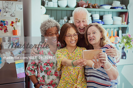 Happy, playful active seniors taking selfie with camera phone, making silly faces