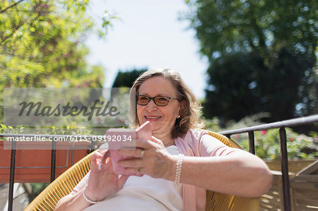 Happy senior woman using smart phone on sunny patio