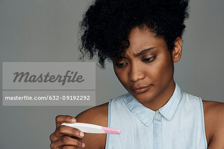 Close-up of young woman looking at pregnancy test strip