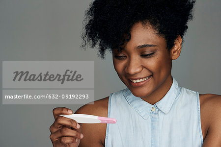 Close-up of young woman looking at pregnancy test strip