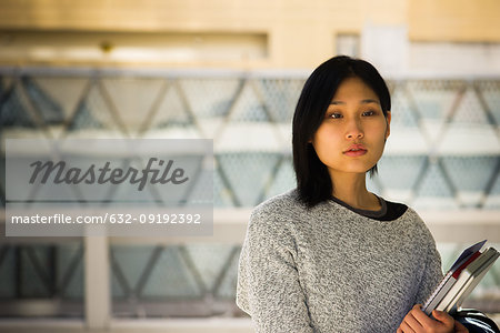 Serious woman holding laptop and file