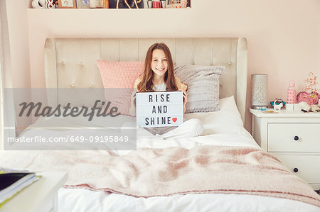 Girl holding up sign in bed