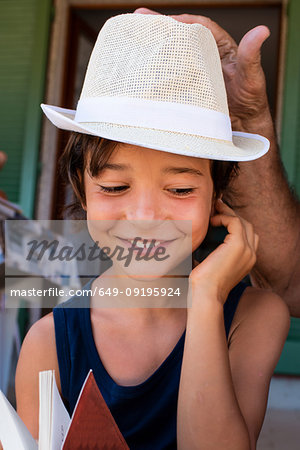 Grandfather placing hat on boy's head