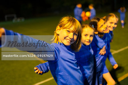 Portrait smiling, confident girls soccer team on field at night