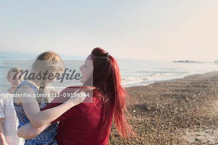 Lesbian couple and daughter on sunny beach