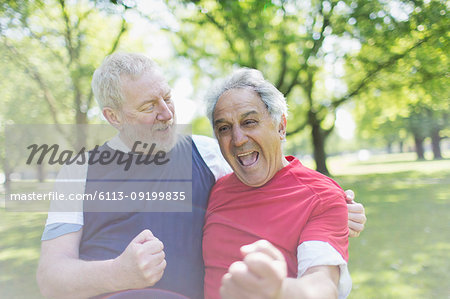 Exuberant active senior men friends cheering in park