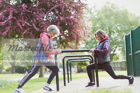 Active senior female runners stretching legs in park