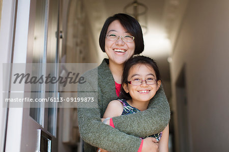 Portrait happy, affectionate mother and daughter hugging in doorway