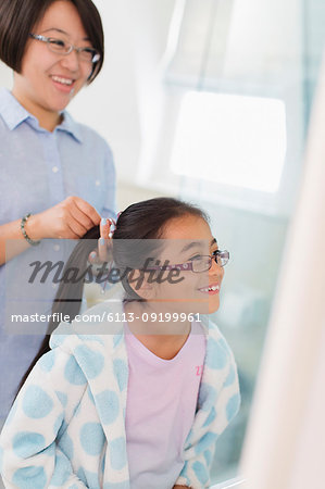 Mother fixing daughters hair in bathroom