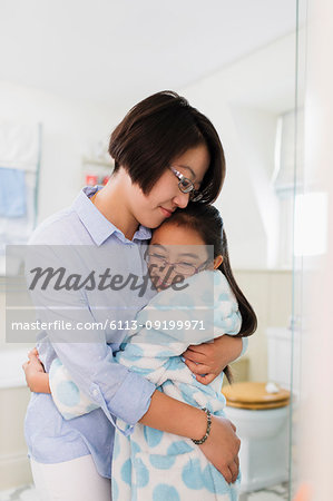 Affectionate mother and daughter hugging in bathroom