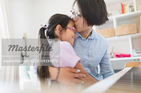 Affectionate mother and daughter hugging, playing piano