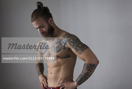 Portrait bare chested man with tattoos and beard