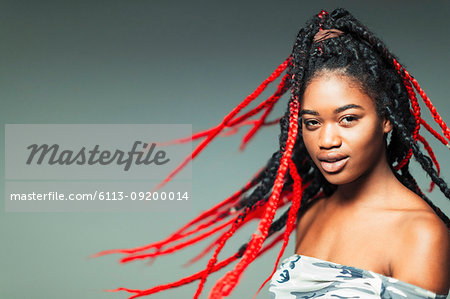 Portrait confident, cool young woman flipping braids