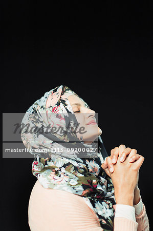 Serene woman in floral hijab praying