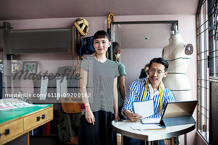 Japanese male and female fashion designers working in a studio.