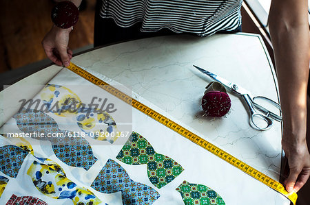 High angle close up of fashion designer working in studio, measuring piece of fabric.