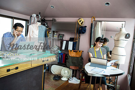 Japanese male and female fashion designers working in a studio.