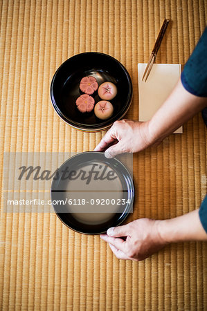 High angle close up of man knelling on floor, holding a bowl with Wagashi, sweets traditionally served during a Japanese Tea Ceremony.