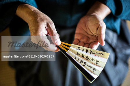 High angle close up of Japanese man wearing kimono holding Sensu fan.