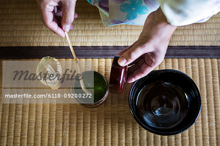 High angle close up of traditional Japanese Tea Ceremony, woman spooning green Matcha tea powder into bowl.