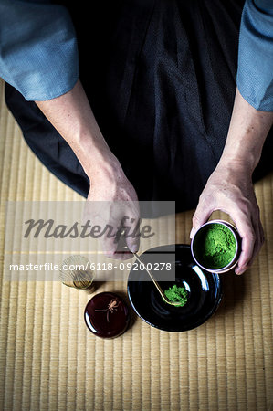 High angle close up of traditional Japanese Tea Ceremony, man spooning green Matcha tea powder into bowl.