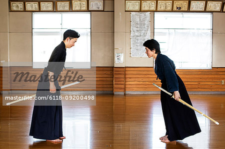 Female Japanese Kendo fighter kneeling on wooden floor, fastening