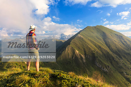 Man on top of Monte Rolla looks to Monte Disgrazia and Sasso Canale, Sondrio province, Valtellina, Lombardy, Italy, Europe