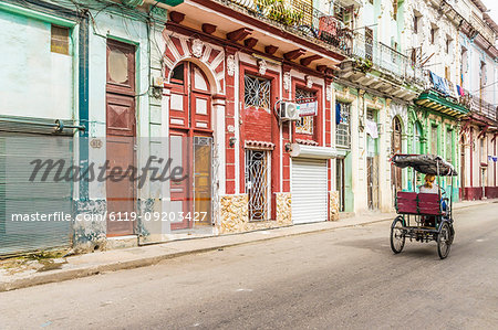 A vintage cycle rickshaw passing beautiful local architecture in Havana, Cuba, West Indies, Caribbean, Central America