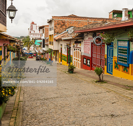 A typically colourful street with buildings covered in traditional local tiles in the picturesque town of Guatape, Colombia, South America