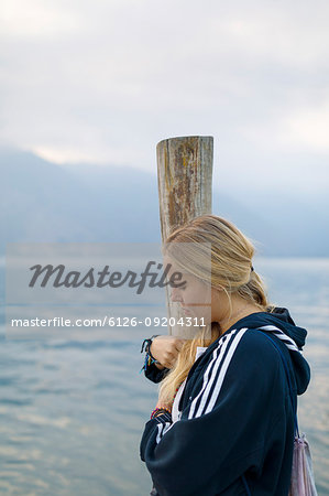 Woman hugging wooden pole at Lake Atitlan, Guatemala