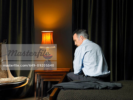 Man sitting on bed with back to camera