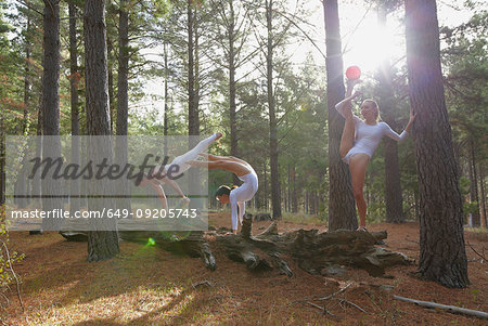 Dancers posing on log in forest