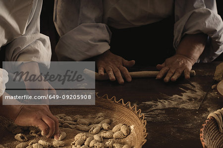 Chefs rolling gnocchi dough in kitchen