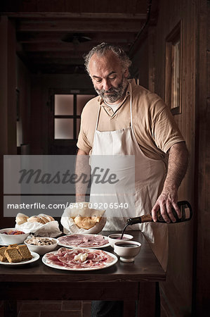 Man laying out meat, bread and sauce