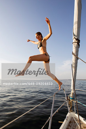 Woman jumping off boat into water