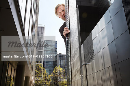 Oversized businessman peering from behind skyscrapers, low angle view