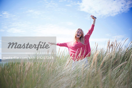 Portrait of woman dancing in marram grass, Wales, UK