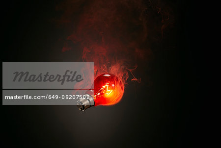 Still life of red smoking illuminated lightbulb