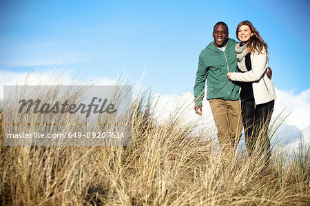 Young couple strolling in sand dunes, Bournemouth, Dorset, UK