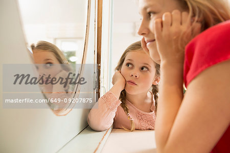 Sisters staring at each other in bedroom mirror