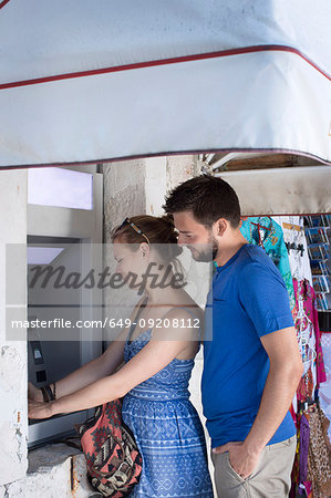 Young couple using street cash machine, Milna, Brac, Croatia