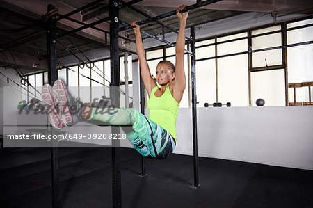 Young female crossfitter training on parallel bars in gym