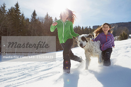 Mother and daughter running with their pet dog