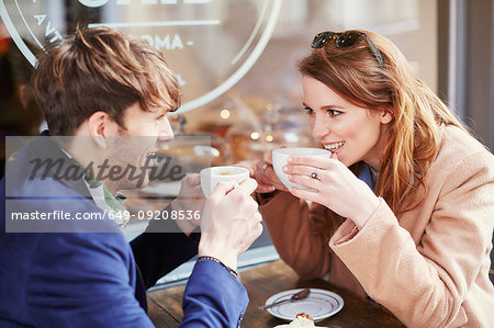 Couple drinking coffee at sidewalk cafe, London, UK