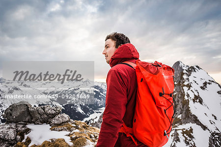 Hiker looking at snow capped mountain range, Kellenspitze, Tannheim mountains, Tyrol, Austria