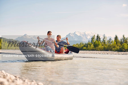 Couple using paddles to steer dinghy on water, Wallgau, Bavaria, germany