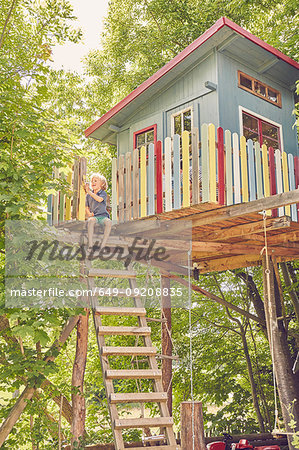 Young boy painting tree house