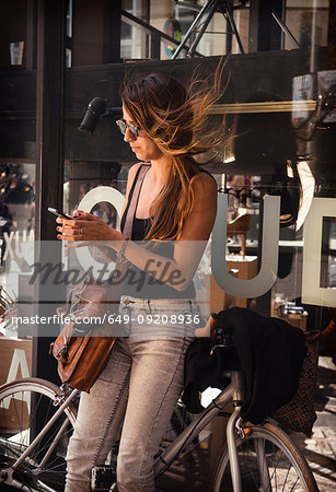 Woman using smartphone outside shop, Barrio Gotico, Barcelona, Spain